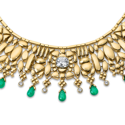 Gold necklace with  center diamond and emerald drops on a white background