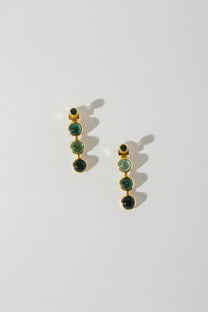 A pair of earrings with three tourmaline stones set in 18k yellow gold jackets, displayed against a white background.