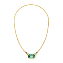 Gold necklace with a green gemstone on a white background